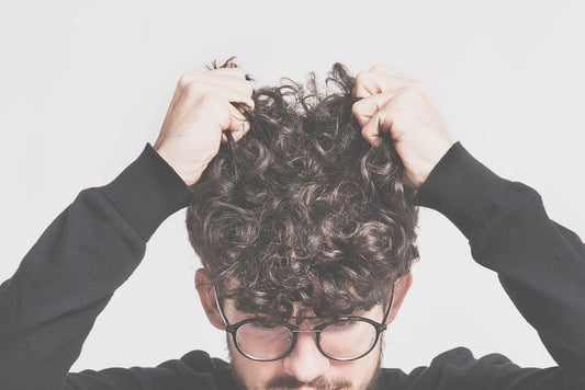 Trichotillomanie - Junge Mann mit Brille juckt seinen Kopf