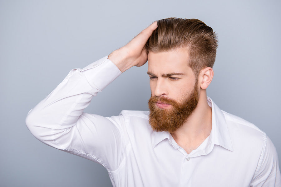 Mann mit Hand am Kopf will Haare schneller wachsen lassen